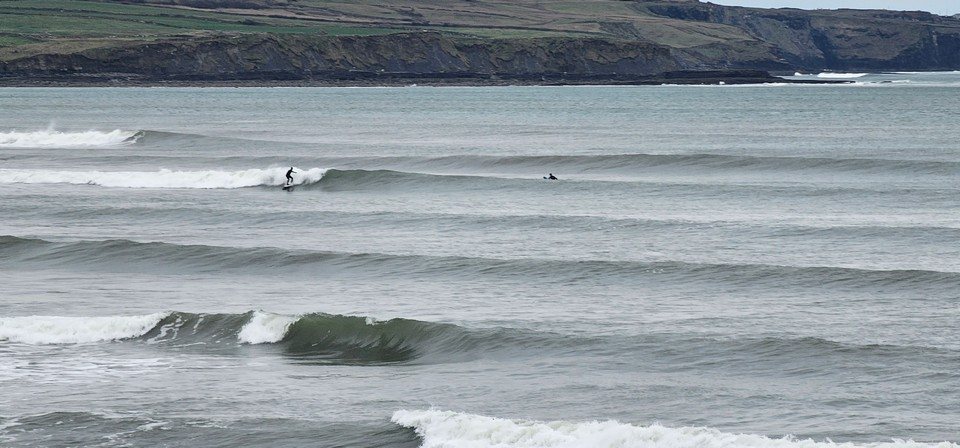 Surfer on a wave at outer cornish as the tide is coming in